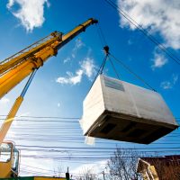 Industrial,Crane,Operating,And,Lifting,An,Electric,Generator,Against,Sunlight